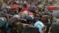 FILE - Migrant workers crowd up outside a bus station as they wait to board buses to return to their villages, in Ghaziabad, on the outskirts of New Delhi, March 28, 2020.