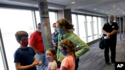 FILE - People wearing masks wait to board a flight in Kansas City, Missouri, May 24, 2020. Governments and businesses are scrambling to change course following new federal guidance calling for the return of mask wearing in virus hot spots.