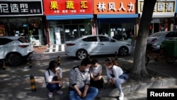 2020年5月13日，北京一个招聘服务中心外几名失业年轻人正在用手机寻找招聘信息。