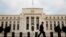 FILE - A man walks past the Federal Reserve Bank in Washington, D.C.