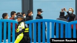 ماموران امنیتی در شهر ووهان، چین تیم دانشمندان سازمان بهداشت جهانی که برای بررسی منشا ویروس کرونا به این شهر سفر کرده است را از نزدیک تحت نظارت دارند. ۳۰ ژانویه ۲۰۲۱ 