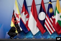 Seorang pekerja terlihat sedang membenarkan posisi bendera Brunei Darussalam sebelum pertemuan dewan koordinasi ASEAN ke-22 di sela-sela KTT ASEAN ke-33 di Singapura. (Foto: AP)