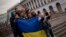 FILE - People holding a Ukrainian flag pose for a photo in Kyiv's Independence Square.