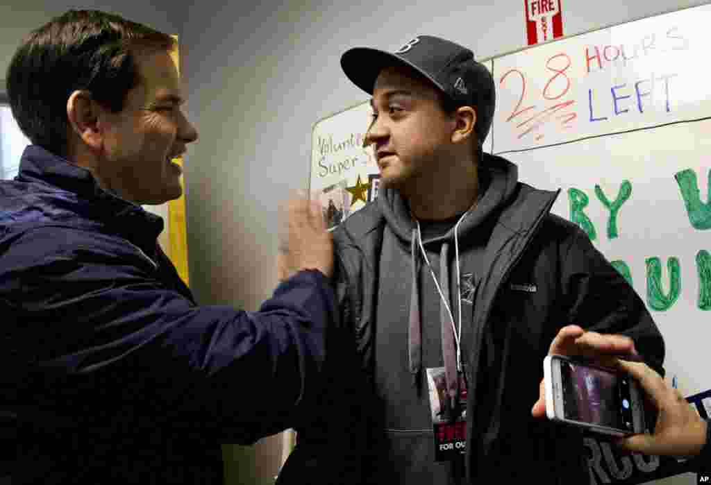 Republican presidential candidate Sen. Marco Rubio, R-Fla., thanks volunteer Chris Ward, 26, of Tampa, Fla., by a white board counting down the hours until the New Hampshire primary at his campaign headquarters in Manchester, N.H., Feb. 8, 2016.