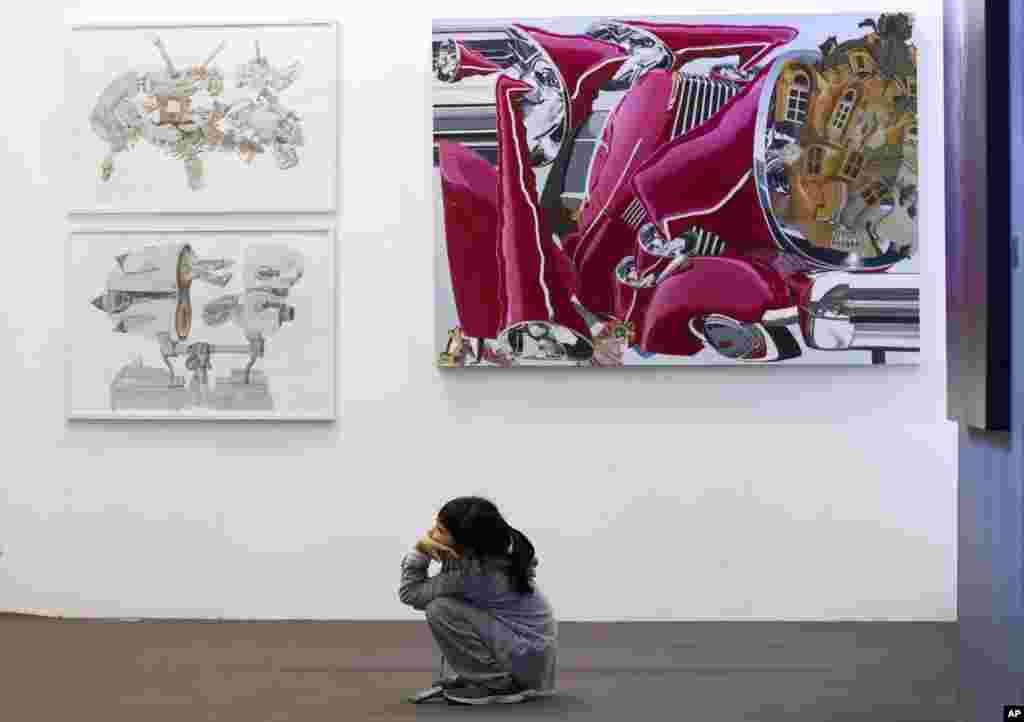 Seorang anak perempuan terkagum-kagum mengamati lukisan bergaya modern pada pameran seni di Beijing, China.