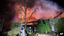 Firefighters stand in front of the burning monkey house at Krefeld Zoo, in Krefeld, Germnay, Jan. 1, 2020.