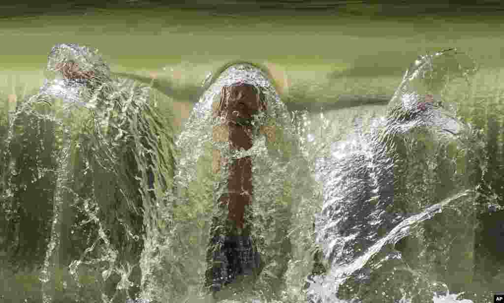 បុរស​ម្នាក់កំពុង​មុជទឹក​នៅ​ក្រោម​ទឹកធ្លាក់​តូចមួយ​នៅ​ក្នុង​សួន​ English ក្នុង​ទីក្រុង​ Munich ប្រទេស​អាល្លឺម៉ង់។​