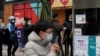 People wearing face masks to help curb the spread of the coronavirus use smartphones to scan their health code and get temperature check before entering a shopping mall in Beijing, Jan. 14, 2021.