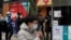 People wearing face masks to help curb the spread of the coronavirus use smartphones to scan their health code and get temperature check before entering a shopping mall in Beijing, Jan. 14, 2021.