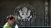 FILE - A Chinese woman checks her documents as she walks past the U.S. Embassy in Beijing, China, May 6, 2011.