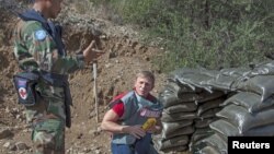 British actor Daniel Craig (R), a UN advocate against use of landmines and explosives, gets a briefing from Cambodian de-miners at an active minefield in Cyprus, Oct. 12, 2015.