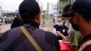 FILE - A U.S. Customs and Border Protection officer examines paperwork of migrants waiting to cross into the United States to request asylum, in Tijuana, Mexico, July 5, 2021.