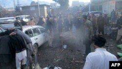 巴基斯坦安全官员和当地居民在帕拉奇纳镇一个市场的爆炸现场。帕拉奇纳镇与阿富汗接壤，是库拉姆部落地区的首府。（2017年1月21日档案照片）