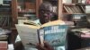 Louis Mukwaya, mosquito researcher at the Uganda Virus Research Institute near Entebbe, reads at his desk about his primary subject of study. (J. Craig/VOA) 