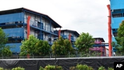 In this Sunday, May 10, 2020, photo, people sit outside a building balcony at the S11@Punggol, a complex of dormitory buildings for foreign workers in Singapore. A second wave of coronavirus infections in tightly packed foreign workers' dormitories…