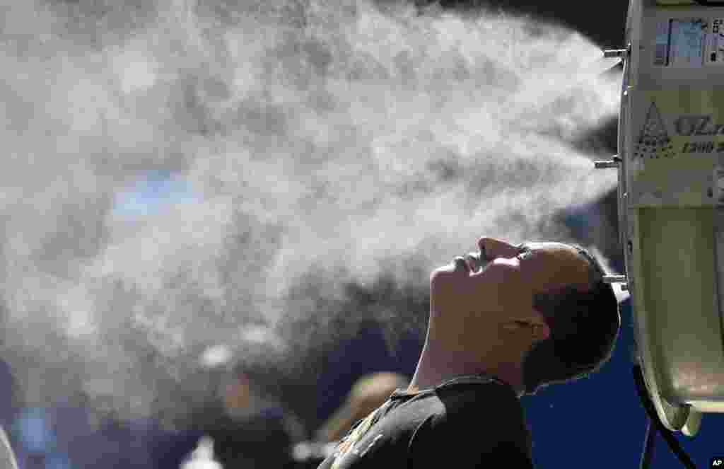 A spectator cools off at a water spraying fan at the Australian Open tennis championships in Melbourne, Australia.