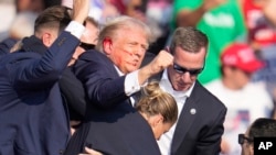 前总统唐纳德·特朗普2024年7月13日在宾夕法尼亚州巴特勒的一场竞选活动上遭遇枪击事件后被安全人员带离走下舞台。