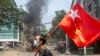 FILE - A man holds a National League for Democracy (NLD) flag during a protest against the military coup, in Yangon, Myanmar March 27, 2021. 