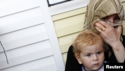 A Syrian refugee woman holding a child cries after fleeing from a refugee camp named "Container City" on the Turkish-Syrian border in Oncupinar in Kilis province, southern Turkey July 22, 2012. 