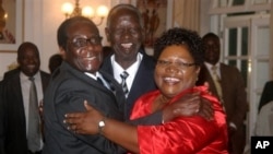 Zimbabwean President Robert Mugabe, left, celebrates with newly sworn-in vice presidents Joyce Mujuru, right, and Joseph Msika, center, State House, Harare, Oct. 2008 file photo.