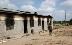 A member of Kenya's security forces walks past a damaged police post after an attack by al-Shabab extremists in the settlement of Kamuthe in Garissa county, Kenya Monday, Jan. 13, 2020