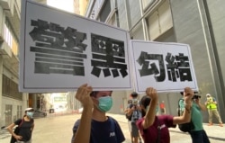 两名年轻人7月19日下午在元朗西铁站附近高举抗议警方的大型标语，他们一度被警方截查 （美国之音/汤惠芸）