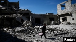 Des gens marchent près de bâtiments détruits dans le quartier de Douma, à Damas, le 4 avril 2017.