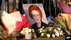 Sebuah potret mendiang "Iron Lady" Margaret Thatcer dan karangan bunga dari masyarakat yang berduka menghiasi pagar rumah kediaman almarhumah di Belgravia, London (8/4). 