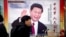 FILE - People walk past a propaganda billboard showing Chinese President Xi Jinping on a street in Beijing, China, March 2, 2018.