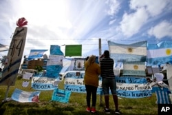 Friends and family of missing submarine crew members place a flag on the fence of the naval base in Mar de Plata, Argentina, Nov. 24, 2017.