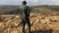FILE - A Hezbollah fighter looks toward Syria while standing in the fields of the Lebanese border village of Brital, May 9, 2015. 