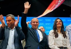Naftali Bennett (C), leader of the Israeli right-wing Yamina ('New Right') party, accompanied by party candidate Ayelet Shaked (R), appears to address supporters at his party's campaign headquarters in Tel Aviv early on March 24, 2021.