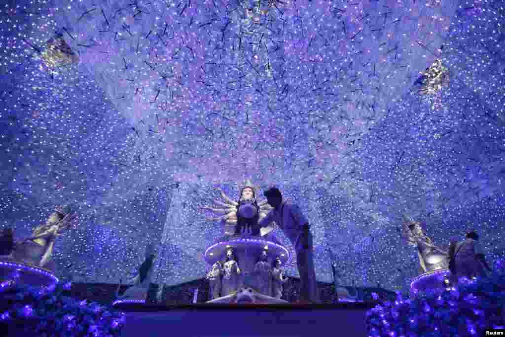 Seniman Rintu Das memberikan sentuhan terakhir kepada patung Dewi Hindu Durga menjelang festival pemujaan Dewi Durga di Kolkata, India.