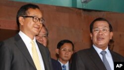 PM Kamboja Hun Sen (kanan) dan pemimpin partai oposisi Kamboja (CNRP), Sam Rainsy (kiri) berpose seusai pertemuan di kantor Senat di Phnom Penh, Kamboja (22/7).