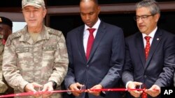 Turkish Chief of Staff General Hulusi Akar, left, Somali prime minister Hassan Ali Khayre, center, and Turkish Ambassador to Somalia Olgan Bekar cut a ribbon to open the Turkey-Somali military training center in Mogadishu, Sept. 30, 2017. 