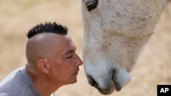Zeljko Ilicic kisses a horse in the Old Hill, sanctuary for horses in the town of Lapovo, in central Serbia, Wednesday, April 3, 2024. (AP Photo/Darko Vojinovic)