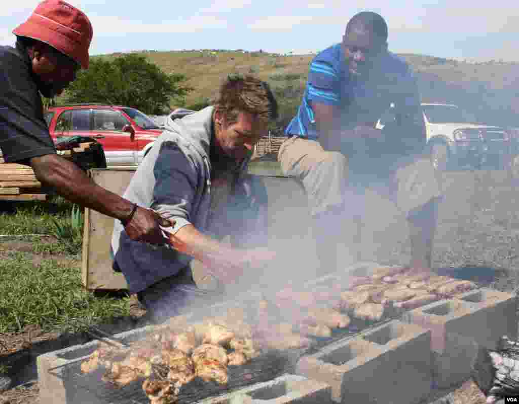 Sisa watches the men barbecue at Ikhaya Loxolo (VOA/ D. Taylor) 