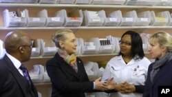 South Africa's Health Minister Aaron Motsoaledi, left, and Secretary of State Hillary Rodham Clinton, speak with Calesa Vinger, and Lizette Monteith about pharmacy procedures in a clinic in Delft South, a suburb of Cape Town, South Africa, Aug. 8, 2012.