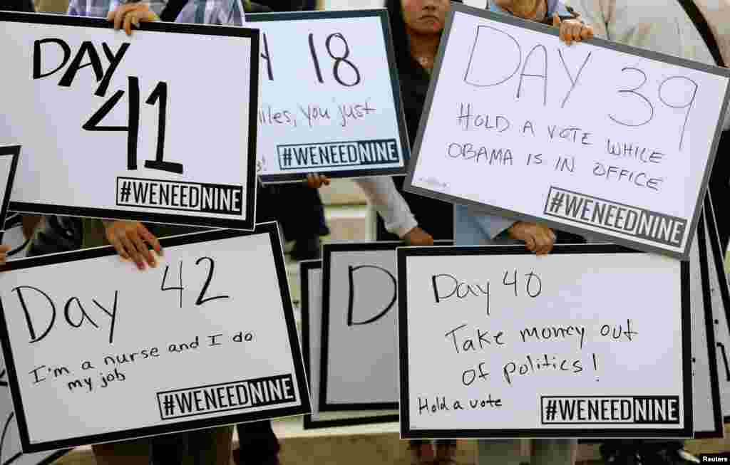 Protesters with We Need Nine, a group calling for the U.S. Senate to allow President Barack Obama to nominate a ninth Supreme Court justice, display their signs in front of the Supreme Court in Washington, D.C.