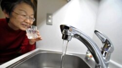 یک زن که لیوانی را از آب شیر در توکیو پر کرده است - ۳ فروردین ۱۳۹۰