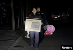 北京的外来务工人员手里提着有限的个人物品被连夜赶出他们在北京通州六环外的住所。（2017年11月23日）