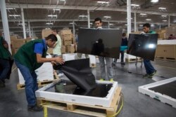 FILE - Workers check screens for faults at an LG flat screen TV assembly plant in Reynosa, Mexico, across the border from McAllen, Texas, March 23, 2017.