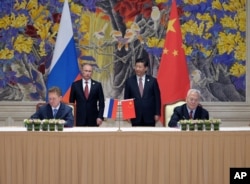 Russia's President Vladimir Putin (Background L) and China's President Xi Jinping (Background R) watch during a signing ceremony in Shanghai, China, May 21, 2014, as Russian Gazprom CEO Alexei Miller, Foreground L) and China's CNPC head Zhou Jiping (Foreg