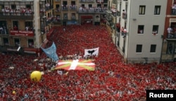 Para peserta festival dengan gembira mengangkat syal merah mereka saat akan dimulainya Festival San Fermin di Pamplona (6/7). Peluncuran roket tradisional "Chupinazo" menandai dibukanya festival yang akan berlangsung hingga 14 Juli mendatang ini.