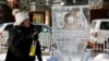 Ice sculptor Deneena Hughes applies the finishing touches with a blow torch to the VOA logo. (Brian Allen/VOA)