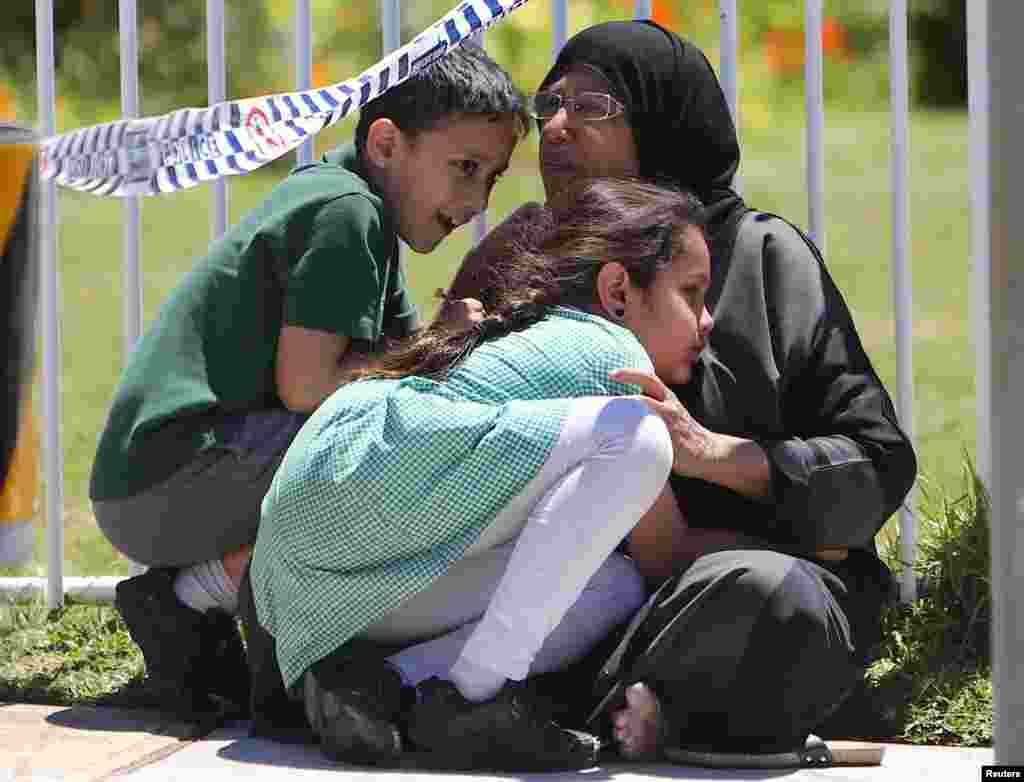 ស្រ្តី​ម្នាក់​អោប​កូនៗ​របស់នាង​នៅ​ក្បែរ​ទីតាំង​ដែល​រថយន្ត​មួយ​គ្រឿង​បុក​ចូល​ទៅក្នុង​សាលាបឋមសិក្សា​ក្នុង​ជាយក្រុង​ស៊ីដនី​ក្នុង​ប្រទេស​អូស្រ្តាលី។