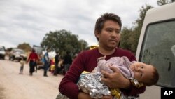 An Afghan man with his baby arrives with other migrants and refugees after crossing a part of the Aegean Sea, from Turkey to Greece.