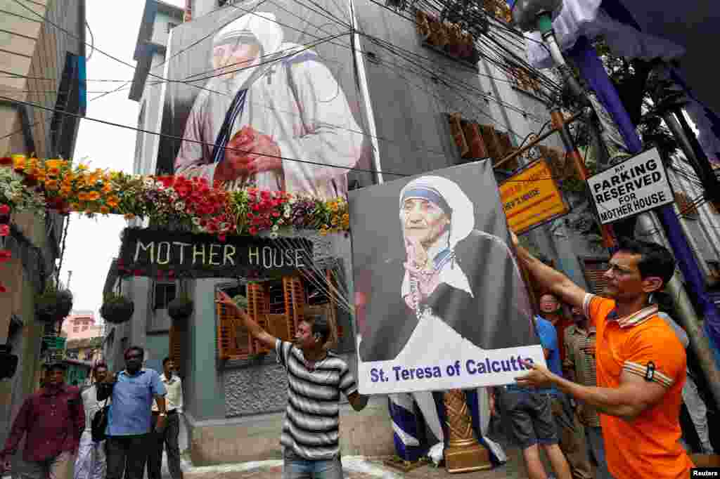 Seorang pria memegang poster Bunda Teresa di luar Misionaris Cinta Kasih di Kolkata, India, selama upacara kanonisasi di Vatikan (4/9).(Reuters/Rupak De Chowdhuri)