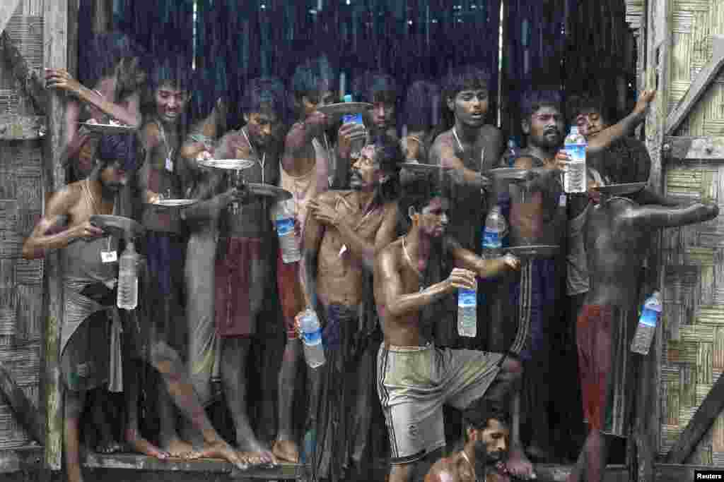 Migrants, who were found at sea on a boat, collect rainwater during a heavy rain fall at a temporary refuge camp near Kanyin Chaung jetty, outside Maungdaw township, northern Rakhine state, Myanmar, June 4, 2015. The migrants were found drifting in the Andaman Sea in an overloaded fishing boat.