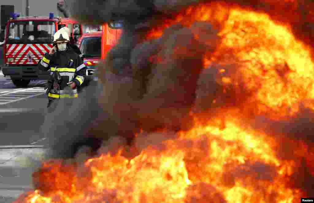 A Belgian firefighter stands behind burning tires as firemen protest for better work conditions in central Brussels. 